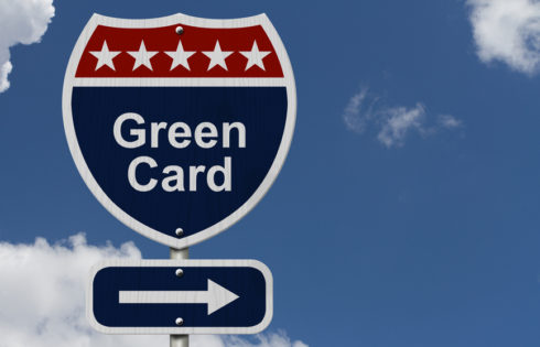 Green Card this way, Blue, Red and White highway sign with words Green Card with sky background